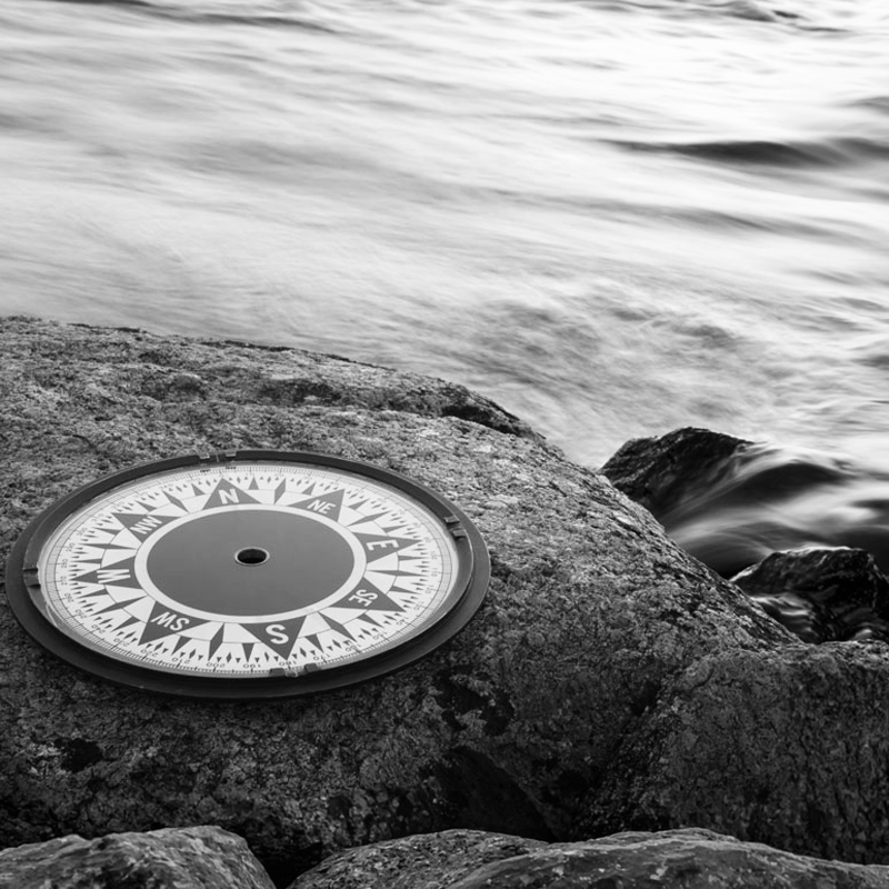 compass on rocks by water